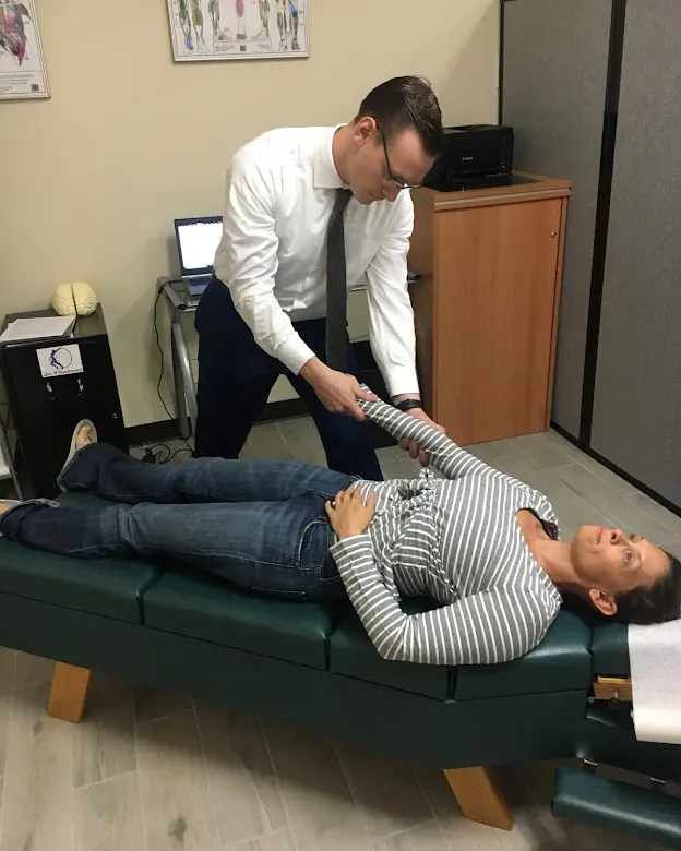 Dr. Michael Brandon holding a patient's arm to check her shoulder and elbow at FIT Clinic in Colts Neck