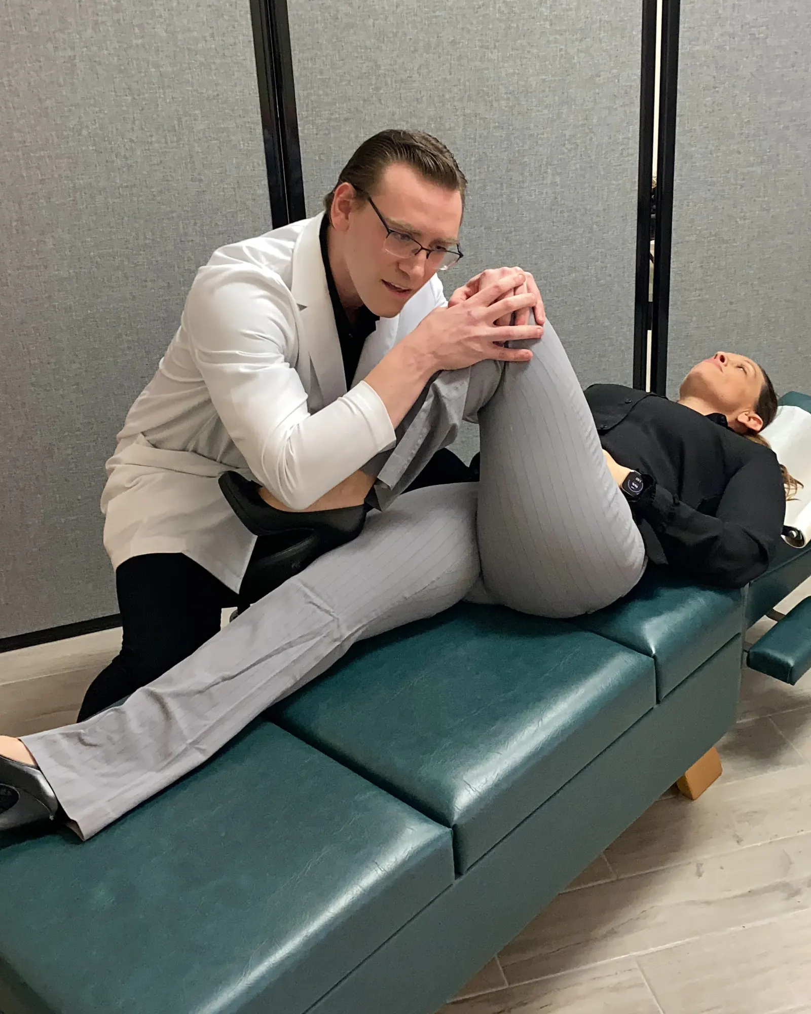 Dr. Michael Brandon bending a patient's knee toward her chest to check hip movement at FIT Clinic in Colts Neck